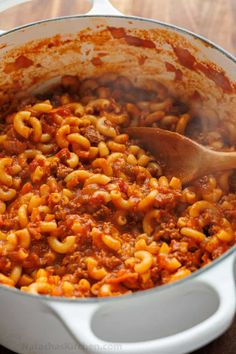 a pot filled with pasta and sauce on top of a wooden table