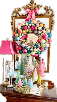 a christmas wreath sitting on top of a wooden table next to a lamp and mirror