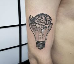 a man's arm with a light bulb and brain tattoo on the left side