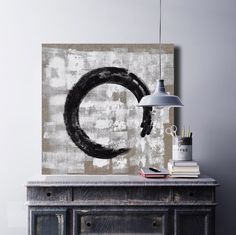 a black and white painting sitting on top of a wooden table next to a lamp