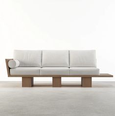 a white couch sitting on top of a wooden frame in an empty room with concrete flooring