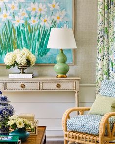 a living room filled with furniture and flowers on top of a wooden table in front of a painting