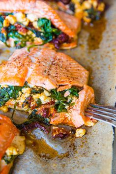 a piece of salmon with spinach and corn on it is being eaten by a fork