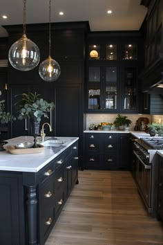 a large kitchen with black cabinets and marble counter tops, lights hanging from the ceiling