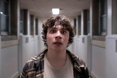 a young man standing in an empty hallway looking at the camera with his mouth open