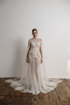 a woman in a wedding dress standing on a wooden floor with a veil over her head