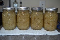 four jars filled with food sitting on top of a white towel next to a sink