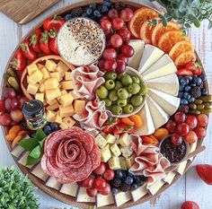 an assortment of cheeses, meats and fruit on a platter