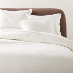 a bed with white sheets and pillows on it