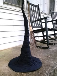 two rocking chairs sitting on the porch with a broom stuck in it's back