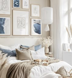 a bedroom with pictures on the wall above it and a bed covered in white linens