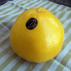 an orange sitting on top of a striped table cloth