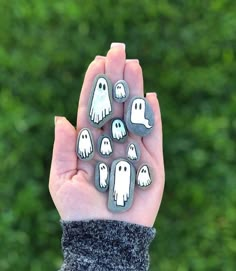 a person holding up some rocks with ghost faces on them in front of a green background