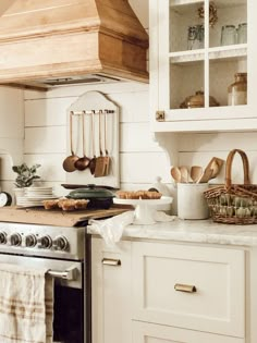 a kitchen with white cabinets and wooden counter tops, an oven hood over the stove