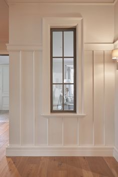 an empty room with wood floors and a window in the wall that has been painted white