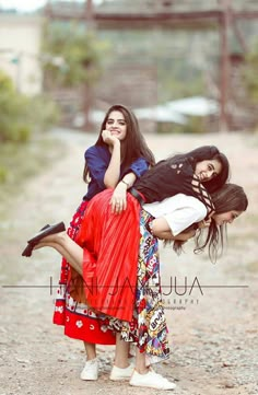 three women are posing for the camera on a dirt road with their legs in the air