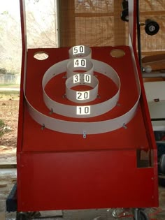 a red machine with numbers on it in front of a window and some other items