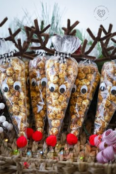 three bags of popcorn with reindeer noses on them sitting in front of candy canes