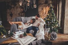 a man and woman sitting on a couch in front of a christmas tree with presents