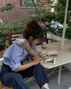 a woman sitting at a table reading a magazine