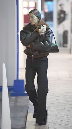 a woman is walking down the sidewalk with her hand in her pocket