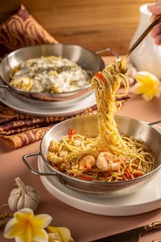 a person is eating noodles with chopsticks in a pan on a table next to other dishes