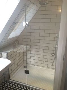 a bathroom with a walk in shower next to a white sink and black and white tiled floor