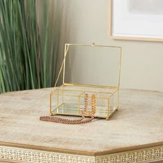 a small gold box sitting on top of a wooden table next to a potted plant