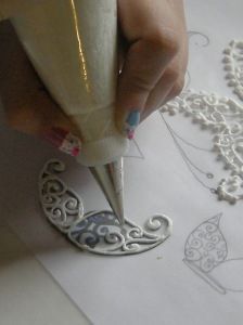 a person writing on paper with a pen in their hand and lace doily behind them