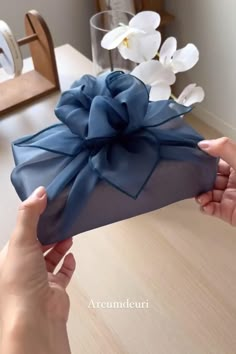 a person holding a blue gift box with a bow on it