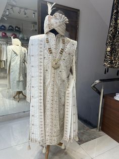 a mannequin dressed in white and gold with an elaborate headdress on display