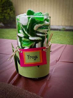 a jar filled with green and white frosted marshmallows on top of a table