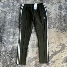 Super Cute Olive Green New Adidas Sst Womens Track Pants Casual Green Bottoms With Three Stripes, Adidas Green Sporty Pants, Green Adidas Sporty Pants, Green Athleisure Bottoms With Side Stripes, Adidas Stretch Sweatpants For Spring, Adidas Stretch Pants With Three Stripes, Green Adidas Cotton Bottoms, Adidas Green Casual Bottoms, Adidas Fitted Sweatpants