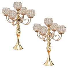 two gold candelabra with crystal balls on each candle holder, one in the shape of a heart