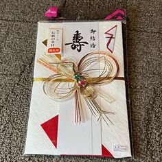 a card with a bow on it sitting on top of a carpeted floor next to a pair of scissors