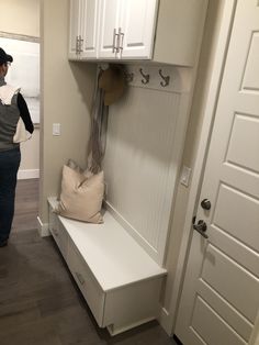 a woman standing in front of a white door next to a bench with a pillow on it