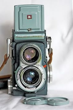 an old camera sitting on top of a white sheet