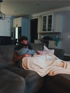 a woman sitting on top of a couch under a blanket