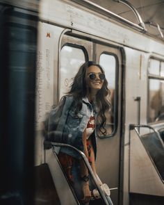 a woman sitting on a subway train looking out the window with her hand in her pocket