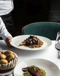 a table topped with plates of food next to wine glasses and utensils on top of a white table cloth