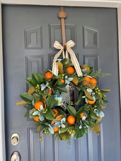 a wreath with oranges and greenery hangs on the front door to welcome guests