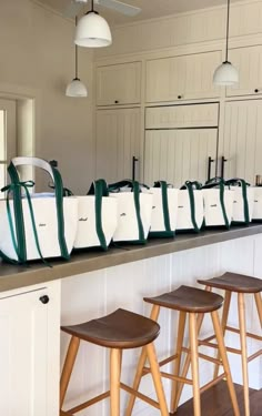 several bags lined up on the counter in a room with white cabinets and stools