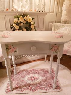 a white table with pink flowers on it in a room next to a chair and rug