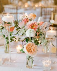 a table with candles and flowers in vases on it's side, surrounded by other tables