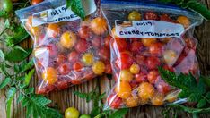 two bags of cherry tomatoes sitting on top of a wooden table next to green leaves