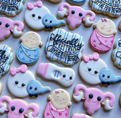 baby shower cookies with blue and pink icing on a white tablecloth that says happy birth