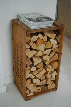 a stack of firewood in a wooden crate on the floor next to a wall