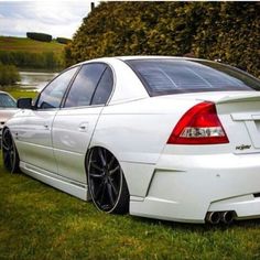 a white car parked on top of a lush green field