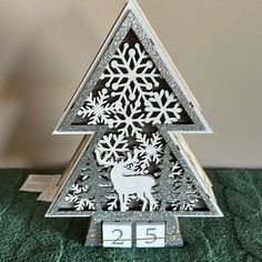 a metal christmas tree with snowflakes on it's sides and a calendar in the shape of a deer