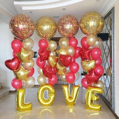 some balloons that are in the shape of hearts and letters with gold, red, and pink colors